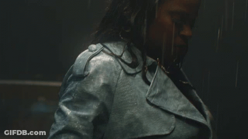 A Woman Wearing A Blue Leather Jacket Is Standing In The Rain GIF
