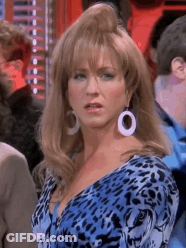 A Woman Wearing A Blue Leopard Print Dress And White Earrings Is Standing In A Crowd . GIF