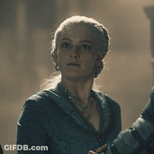 A Woman Wearing A Blue Necklace And Earrings Looks At The Camera GIF