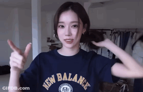 A Woman Wearing A Blue New Balance Shirt Is Giving A Thumbs Up . GIF