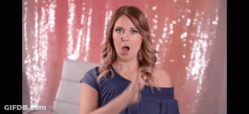 A Woman Wearing A Blue Off The Shoulder Top Is Clapping Her Hands GIF