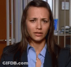 A Woman Wearing A Blue Shirt And A Suit Is Making A Sad Face . GIF