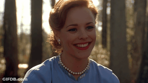 A Woman Wearing A Blue Shirt And Pearls Smiles For The Camera GIF