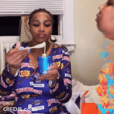 A Woman Wearing A Blue Shirt That Says Backwoods On It Is Eating Something GIF