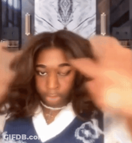 A Woman Wearing A Blue Sweater And A Choker Is Holding Her Hair . GIF