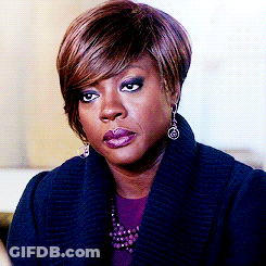 A Woman Wearing A Blue Sweater And Earrings Looks Serious GIF