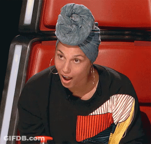 A Woman Wearing A Blue Turban And Earrings Is Sitting In A Red Chair . GIF