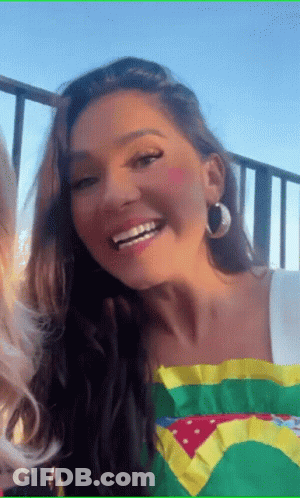 A Woman Wearing A Brazilian Flag Shirt And Hoop Earrings Smiles GIF