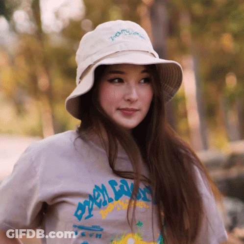 A Woman Wearing A Bucket Hat And A T-Shirt That Says " Tony Hawk " On It GIF