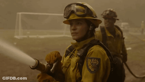 A Woman Wearing A Cal Fire Uniform Holds A Hose GIF