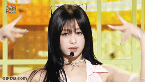 A Woman Wearing A Cat Ear Necklace And A Microphone On Stage . GIF