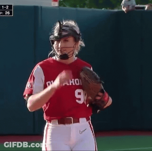 A Woman Wearing A Catcher 'S Helmet And Glove Stands On The Field GIF