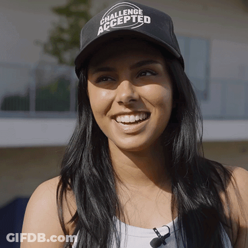 A Woman Wearing A Challenge Accepted Hat Smiles GIF