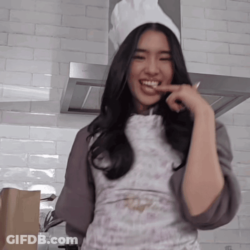 A Woman Wearing A Chef 'S Hat And Apron Is Smiling In A Kitchen GIF