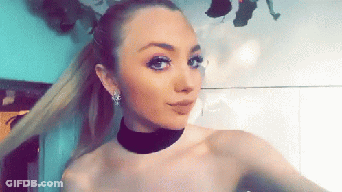 A Woman Wearing A Choker And Earrings Takes A Selfie GIF