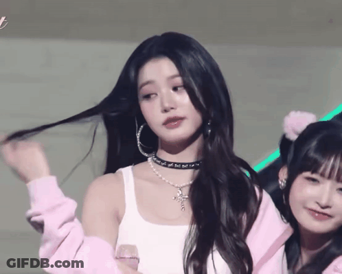 A Woman Wearing A Choker And Hoop Earrings Is Standing Next To Another Girl GIF