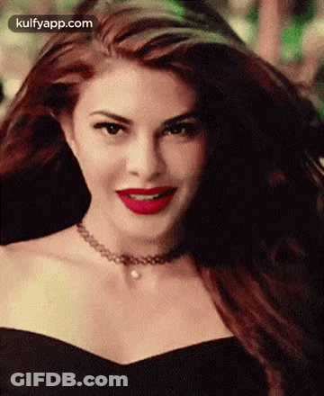 A Woman Wearing A Choker And Red Lipstick Is Smiling . GIF