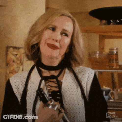 A Woman Wearing A Choker Is Holding A Pair Of Scissors And Smiling . GIF