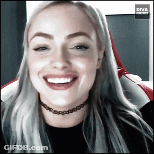 A Woman Wearing A Choker Is Smiling In Front Of A Diva Banner GIF