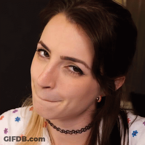 A Woman Wearing A Choker Necklace And Earrings Makes A Funny Face GIF