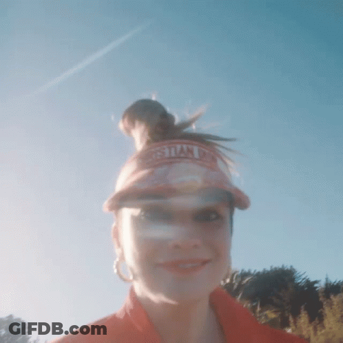 A Woman Wearing A Christian Dior Visor Stands In Front Of A Blue Sky GIF