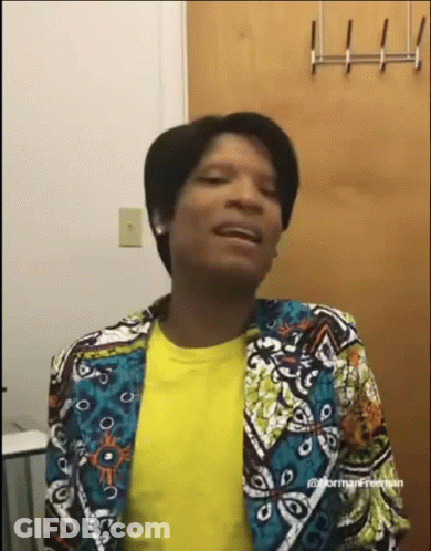 A Woman Wearing A Colorful Jacket And A Yellow Shirt Is Making A Funny Face . GIF