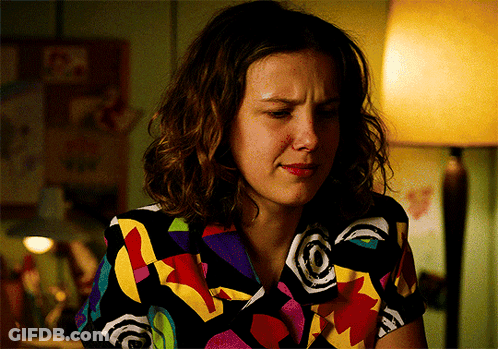 A Woman Wearing A Colorful Shirt Is Sitting In A Dark Room GIF