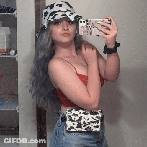 A Woman Wearing A Cow Print Hat Takes A Selfie With Her Phone GIF
