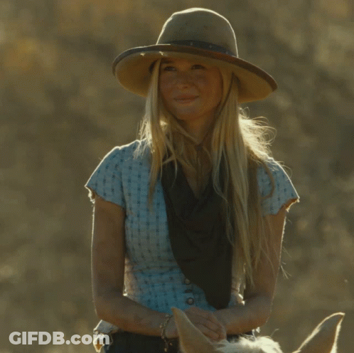 A Woman Wearing A Cowboy Hat And A Blue Shirt Is Riding A Horse GIF