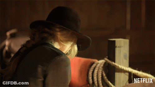 A Woman Wearing A Cowboy Hat Is Standing Next To A Netflix Logo GIF