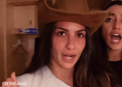A Woman Wearing A Cowboy Hat Is Standing Next To Another Woman Wearing A White Shirt . GIF