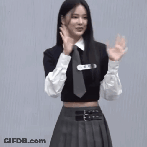A Woman Wearing A Crop Top And Tie Is Waving Her Hands GIF