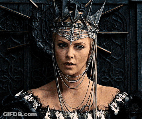 A Woman Wearing A Crown And A Black Dress Looks At The Camera GIF