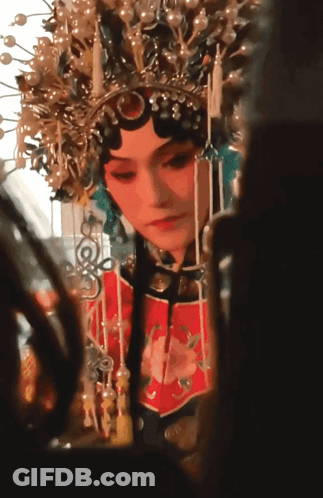A Woman Wearing A Crown And A Red Dress Looks At Herself In A Mirror GIF
