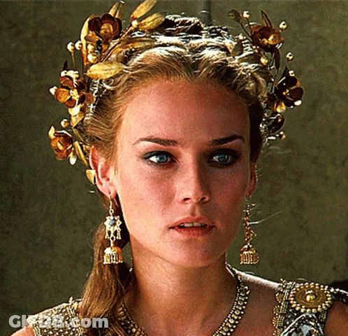 A Woman Wearing A Crown Of Gold Flowers And Earrings GIF