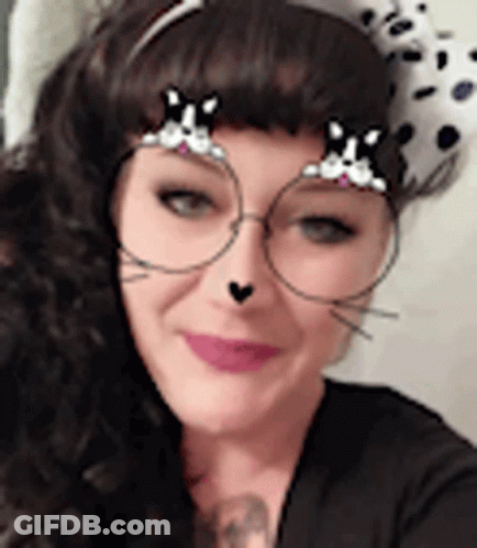 A Woman Wearing A Dalmatian Hat And Glasses With A Cat Face Filter On Her Face . GIF