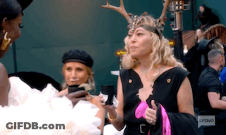 A Woman Wearing A Deer Headband Is Standing Next To Another Woman Holding A Cell Phone . GIF