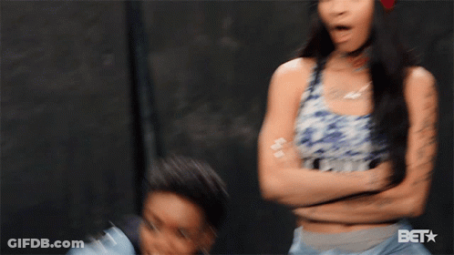 A Woman Wearing A Denim Jacket Is Smiling With The Bet Logo Behind Her GIF