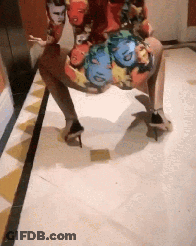 A Woman Wearing A Dress With Faces On It Is Dancing On The Floor GIF
