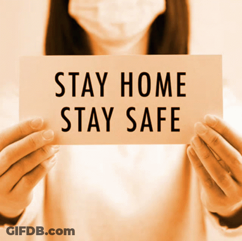 A Woman Wearing A Face Mask Is Holding A Sign That Says Stay Home Stay Safe GIF