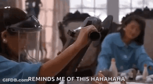 A Woman Wearing A Face Shield Is Holding A Camera In Front Of Another Woman . GIF