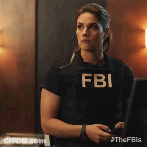 A Woman Wearing A Fbi Vest Is Standing In Front Of A Computer GIF