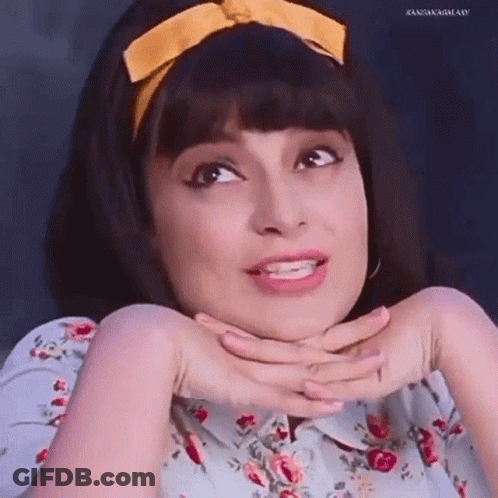 A Woman Wearing A Floral Shirt And A Yellow Headband Is Making A Funny Face With Her Hands On Her Chin . GIF