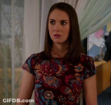 A Woman Wearing A Floral Shirt Is Looking At Something GIF