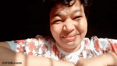 A Woman Wearing A Floral Shirt Is Smiling And Making A Face GIF