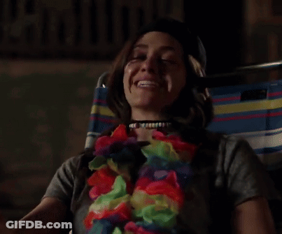 A Woman Wearing A Flower Lei And A Choker Is Laughing GIF