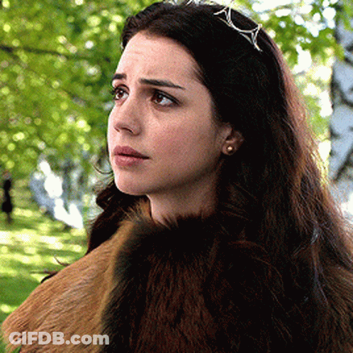 A Woman Wearing A Fur Coat And A Tiara Is Standing In A Park GIF