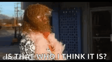 A Woman Wearing A Fur Coat Is Standing In Front Of A Building And Asking Is That Who I Think It Is ? GIF