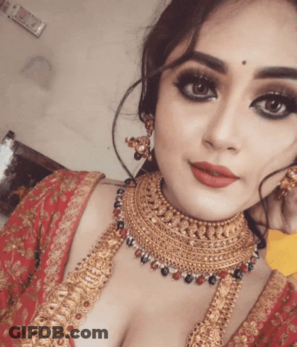 A Woman Wearing A Gold Necklace And Earrings Is Taking A Selfie GIF