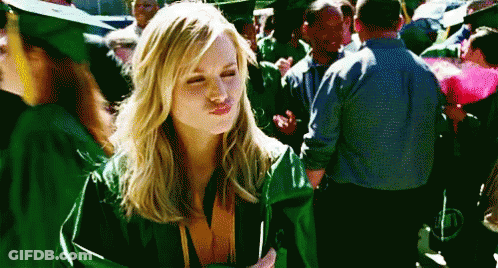 A Woman Wearing A Green Graduation Cap And Gown Is Blowing A Kiss GIF